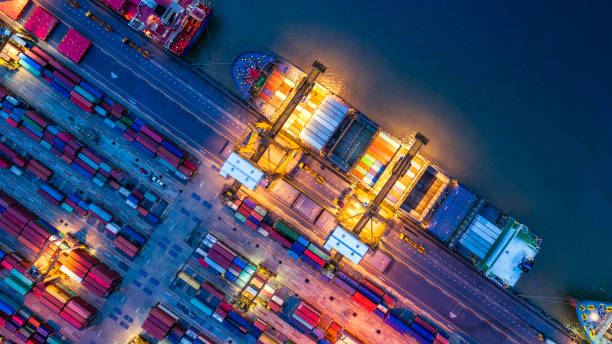 container ship in import export and business logistics, by crane, trade port, shipping cargo to harbor, aerial view from drone, international transportation, business logistics concept - aerial container ship imagens e fotografias de stock