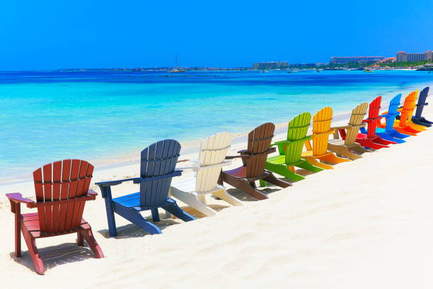 созерцание: пляж с красочными открытыми стульями адирондак - аруба, карибское море - аруба стоковые фото и изображения