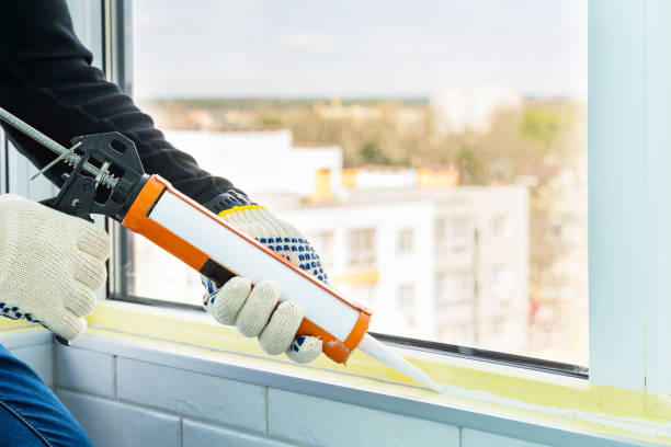 Contractor hand holding glue gun with silicone to repair tile and window. Installation or renovation interior concept. stock photo