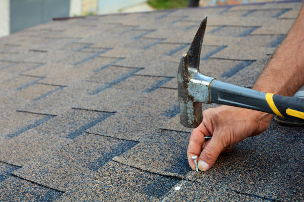 Contractor installing bitumen roof shingles with hammer and nails. stock photo