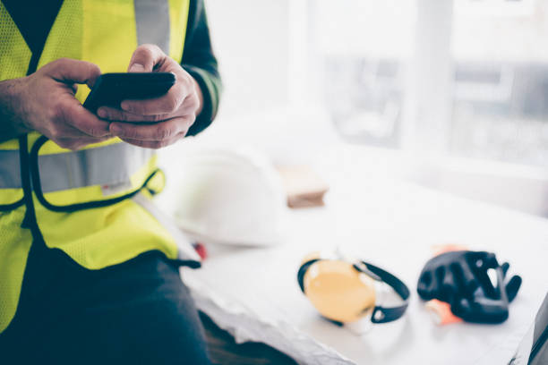 Contractor using his phone to manage the construction work stock photo