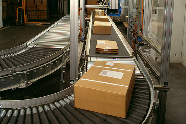 Conveyor belt curve showing brown packed postal boxes Conveyor belt for postal boxes conveyor belt stock pictures, royalty-free photos & images