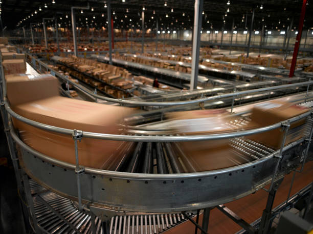 Conveyor System Boxes speed by on the conveyor system at a warehouse. conveyor belt photos stock pictures, royalty-free photos & images