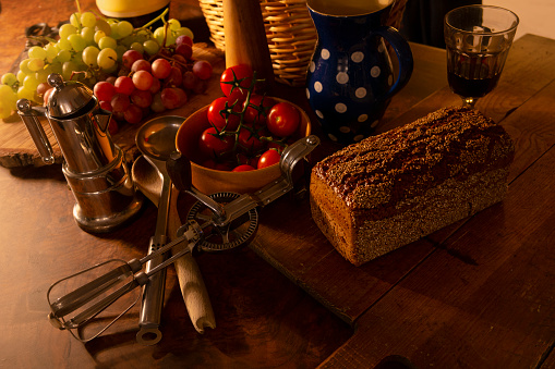 Table scene with cooking utensils, bread, fruits, vegetables, wicker basket