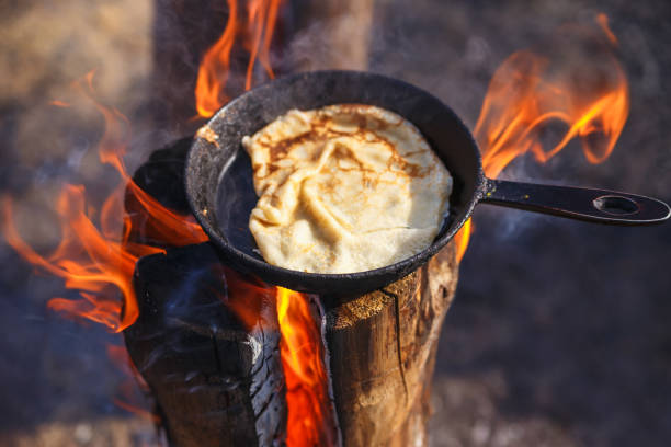 Cooking pancake in a pan on the fire of a Finnish candle stock photo