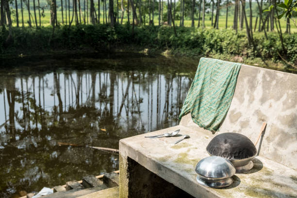 grytor, skedar och en trasa som är torr på en betong bänk av steg till dammen eller ghat i en by på landsbygden bangladesh. - cooking step by step bildbanksfoton och bilder