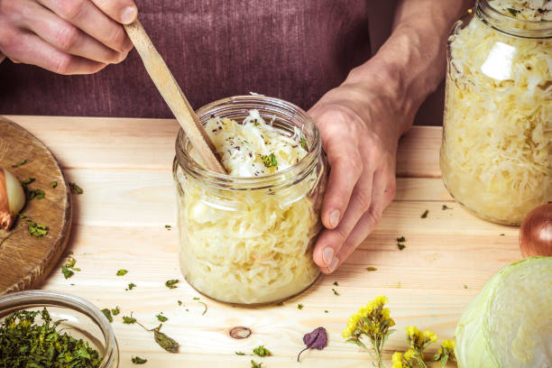 Cooking sauerkraut. Close-up of cropped hands and cabbage in a jar. stock photo
