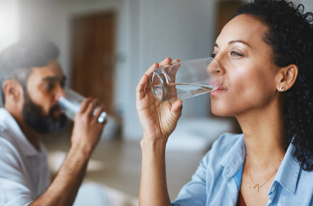 Cool, clean and refreshing Shot of a couple drinking glasses of water together at home drinking water photos stock pictures, royalty-free photos & images