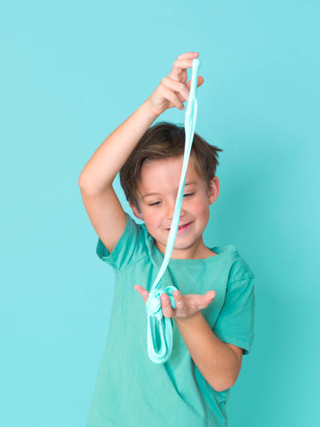 cool, pretty boy plays with homemade slime in front of a blue background stock photo