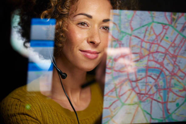 co-ordinating freight a female logistics worker is organising dispatch of freight on her interactive digital map whilst talking on her headset. person looking at map stock pictures, royalty-free photos & images