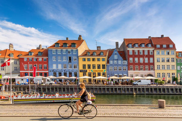 копенгаген знаковых зрения. знаменитый старый порт нюхавн с красочными средневековыми домами, туристическим судном и женщиной на велосипе - copenhagen стоковые фото и изображения
