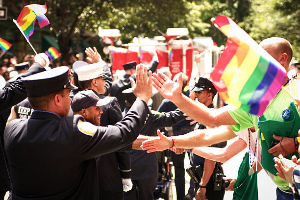 Cops high-fiving crowd during gay pride New York, New York, USA - June 24, 2012: Cops giving high-fives to crowd during Gay Pride Parade on Christopher Street with rainbow flags waiving. nyc pride parade stock pictures, royalty-free photos & images