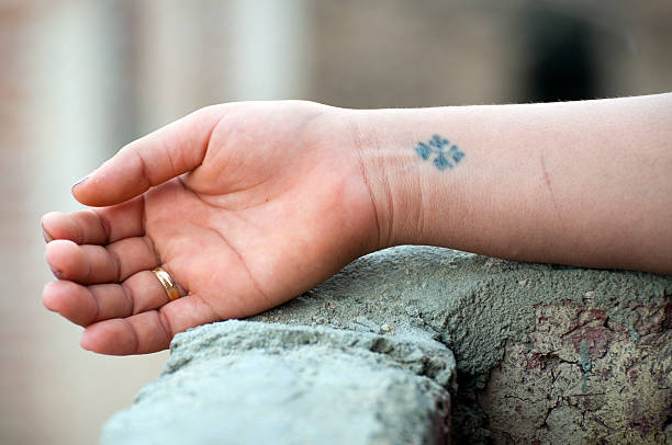 Coptic cross tattoo on woman's wrist in Egypt A young Egyptian woman shows her cross tattoo, which is found on most of the several million Coptic Orthodox Christians in Egypt. coptic stock pictures, royalty-free photos & images