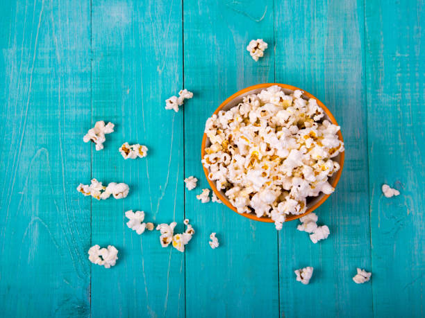 corn popcorn on a blue wooden background, as a snack for watching movies stock photo