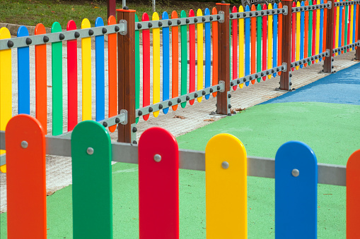 Corner and perspective of multicolored fence
High angle view of multicolored fence surrounding a children playground, green soft flooring. Galicia, Spain.