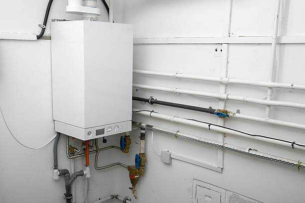 Corner of a room with white boiler and connectors stock photo