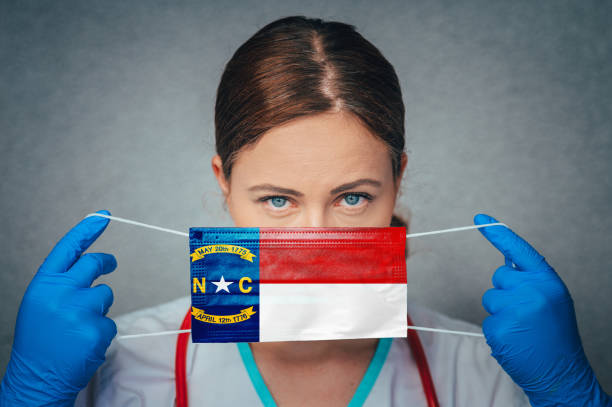 Coronavirus in U.S. State North Carolina, Female Doctor Portrait, protect Face surgical medical mask with North Carolina Flag. Illness, Virus Covid-19 in North Carolina Coronavirus in U.S. State North Carolina, Female Doctor Portrait, protect Face surgical medical mask with North Carolina Flag. Illness, Virus Covid-19 in North Carolina north carolina us state photos stock pictures, royalty-free photos & images