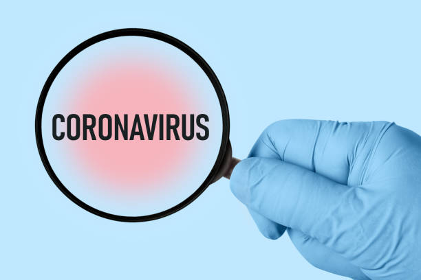 "Coronavirus" inscription on a blue background, doctor's hand with a magnifier. Medical concept of viral infection. stock photo