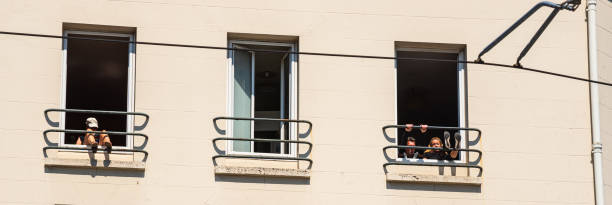 Coronavirus lockdown end, start of deconfinement (easing restrictions). People workout and relaxing in residential building windows in Parisian suburb in sunny day. stock photo