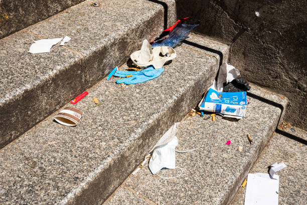 Coronavirus lockdown, start of deconfinement (easing restrictions). Protective mask, disposable gloves, milk carton, coffee cup thrown away on street stairs. stock photo