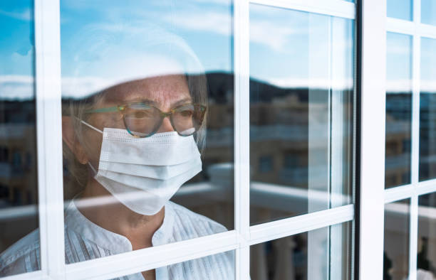 pandemia di coronavirus, donna anziana in auto quarantena per evitare il contagio dell'infezione da virus covid-19. rimane a casa guardando all'aperto dalla finestra. concetto di prevenzione - lockdown foto e immagini stock