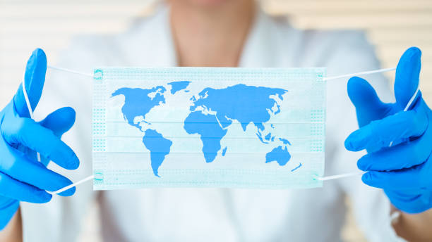Laboratory worker holding protective mask with world map