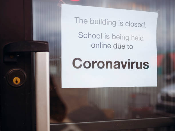 コロナウイルスCOVID-19パンデミックによって閉鎖されていることを示す看板を持つ学校へのドア。