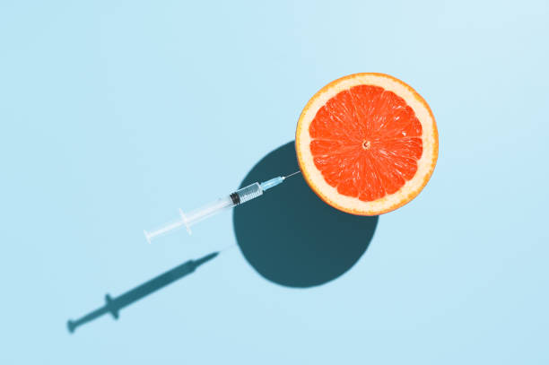 coronavirus vaccination kreativt koncept. hälften grapefrukt och en spruta med vaccin mot covid-19, svävande över pastellblå bakgrund. minimalistisk bild, överst - food sticks bildbanksfoton och bilder