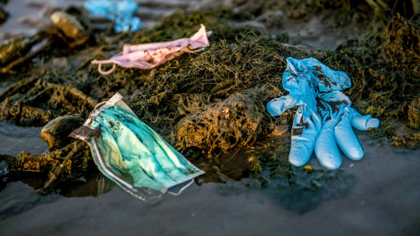 Coronavirus waste polluting the environment. Disposable masks trash sea Coronavirus plastic waste polluting the environment. Disposable masks outbreak trash in the ocean. Discarded used disposable medical mask floats in sea waters contamination photos stock pictures, royalty-free photos & images