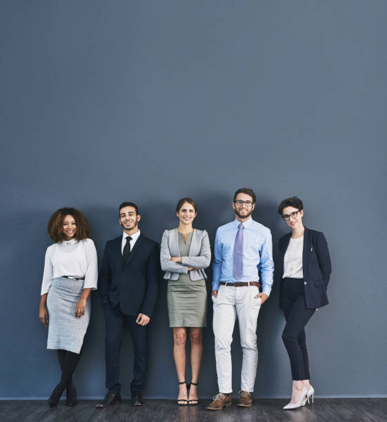 Corporate confidence at it's best Studio shot of a group of businesspeople standing in line against a gray background formalwear photos stock pictures, royalty-free photos & images