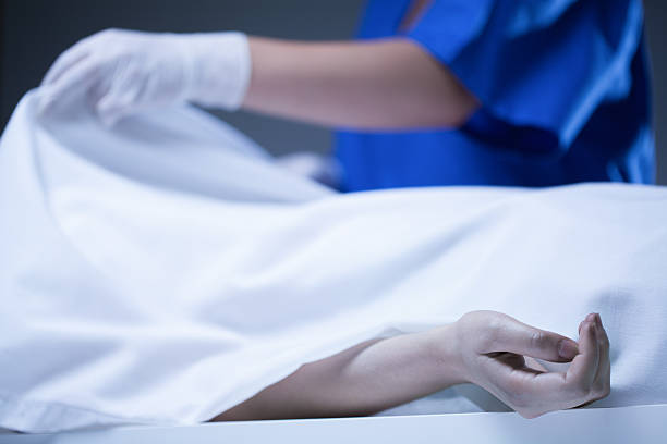Corpse covered by sheet Worker of morgue covering corpse by sheet dead people stock pictures, royalty-free photos & images