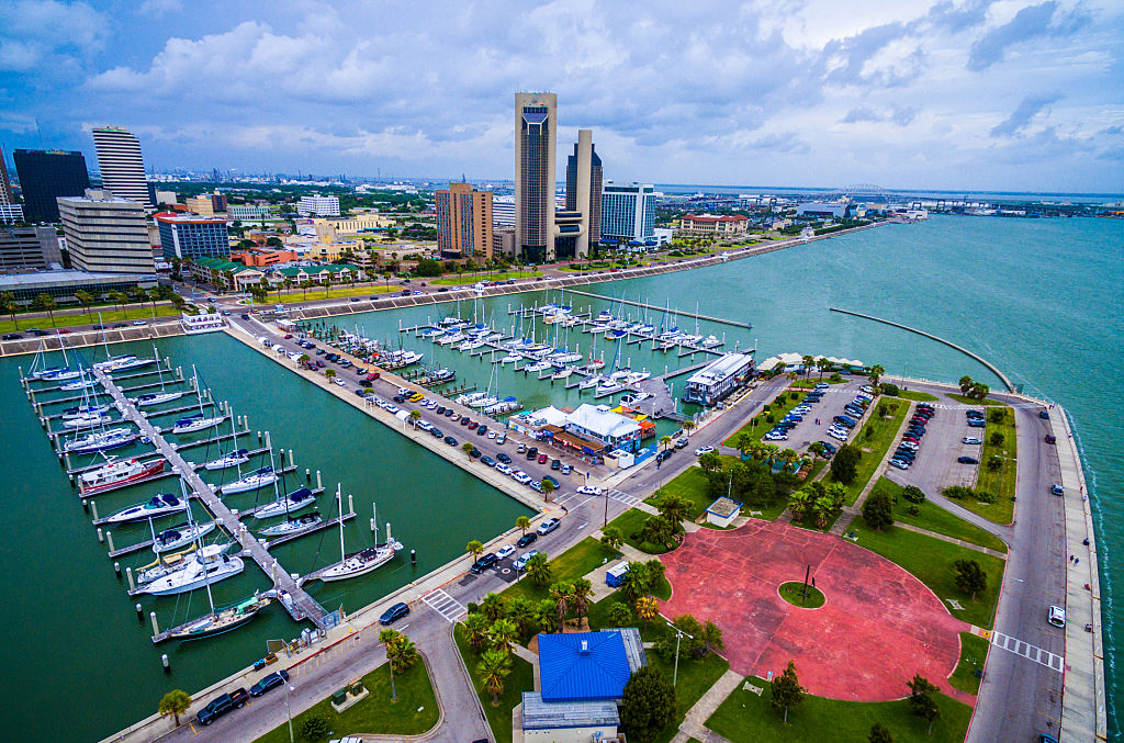 Corpus Christi Texas Aerial Over Marina With a Circle pattern on the T-head and Sailboats and Yatch's on the marina on an amazing day with the CCTX skyline cityscape background and the Harbor Bridge in the distance. Coastal Small Town Paradise vibe. 