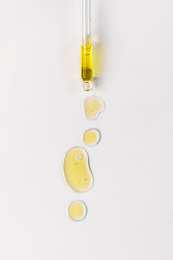 Cosmetic oil bubbles and dropper with oil on white background. Abstract drops of skin care oil.
