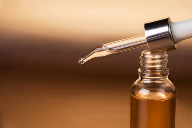 Cosmetic pipette close-up and bottle of cosmetic product, oil or hyaluronic acid on a gold background. Cosmetic pipette close-up and bottle of cosmetic product, oil or hyaluronic acid on a gold background retinol skincare stock pictures, royalty-free photos & images