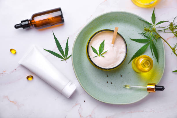 Cosmetics with cannabis oil on a turquoise plate on a light marble background. Copy space, mockup. stock photo