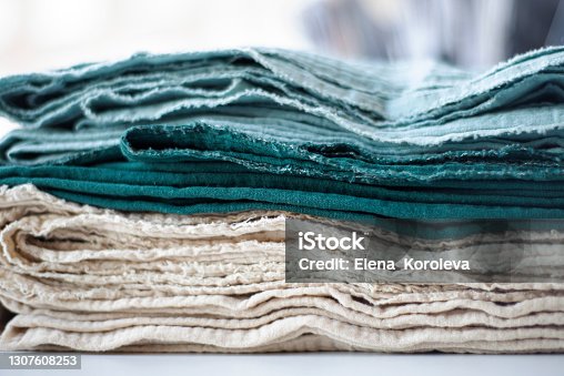 istock Cotton textiles in shades of green and beige in a stack. Organic cotton for the textile industry. Towels plaids sheets muslin clothes. 1307608253