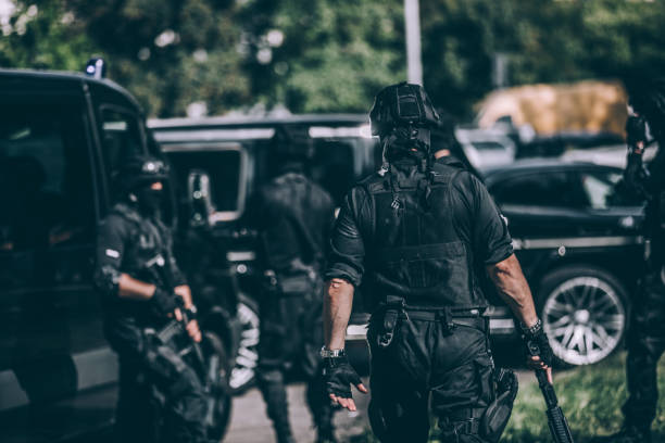 Counter-terrorists team Group of men, special forces armed team, standing by police vehicles, ready for action. special forces stock pictures, royalty-free photos & images