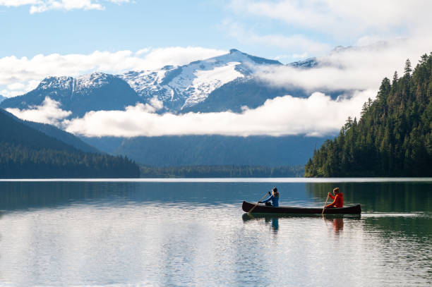Couple canoeing on lake against beautiful mountain stock photo