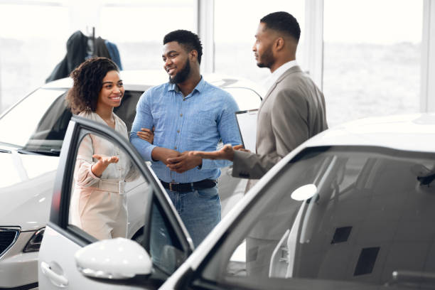 Couple Choosing Car Consulting With Professional Auto Salesman In Dealership Buying Vehicle. African Family Couple Choosing Car Consulting With Professional Auto Salesman In Dealership Center. Selective Focus car salesperson stock pictures, royalty-free photos & images