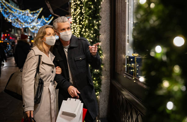 paar weihnachtseinkäufe mit einer gesichtsmaske in london - einzelhandel öffentliches gebäude stock-fotos und bilder
