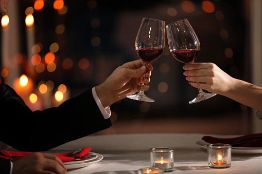 Couple clinking glasses at Valentine's day dinner in restaurant, closeup