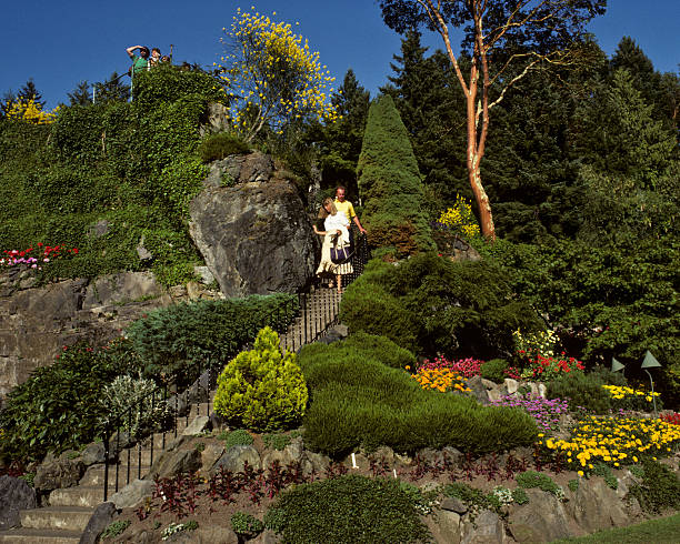 Couple Descending a Staircase at Butchart Gardens Victoria, British Columbia, Canada - August 29, 1983: A couple descends a staircase at Victoria's beautiful Butchart Gardens in the evening. jeff goulden people stock pictures, royalty-free photos & images