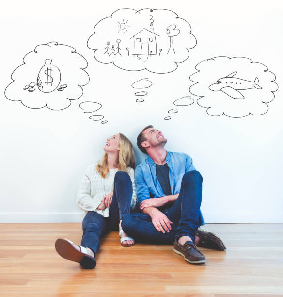 Couple dreaming of family, wealth and travel. Couple dreaming of family, wealth and travel. They are sitting together imagining a new house; money and overseas travel. They are happy and smiling day dreaming stock pictures, royalty-free photos & images