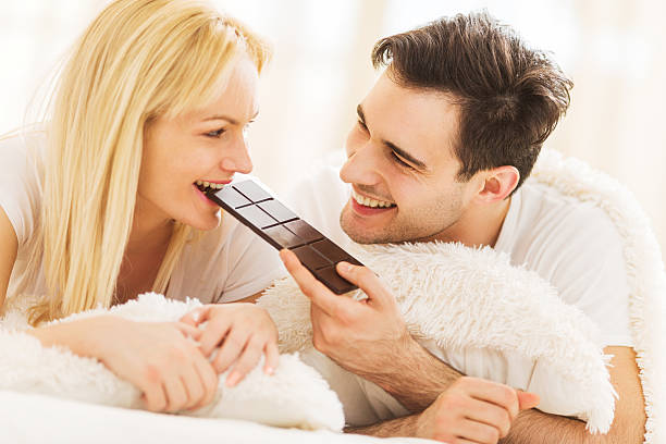 Couple eating chocolate. Young man feeding his girlfriend with chocolate.   couple eating chocolate stock pictures, royalty-free photos & images