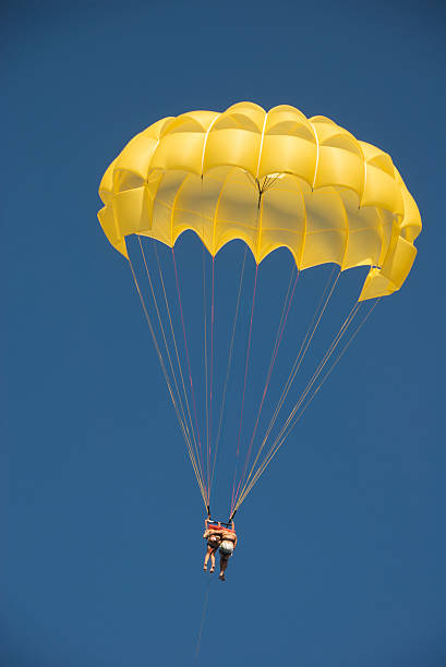 Couple Falling Together in Yellow Parachute Blue Sky stock photo