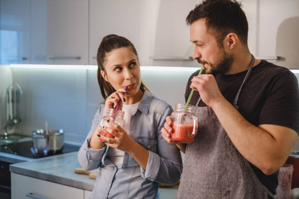 Couple flirting in the kitchen while drinking smoothie stock photo