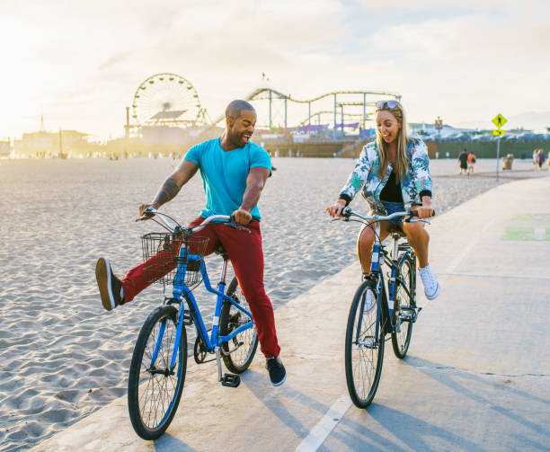 couple having fun riding bikes together at santa monica california stock photo
