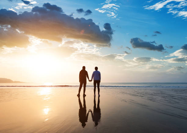 Couple holding hands at beach stock photo