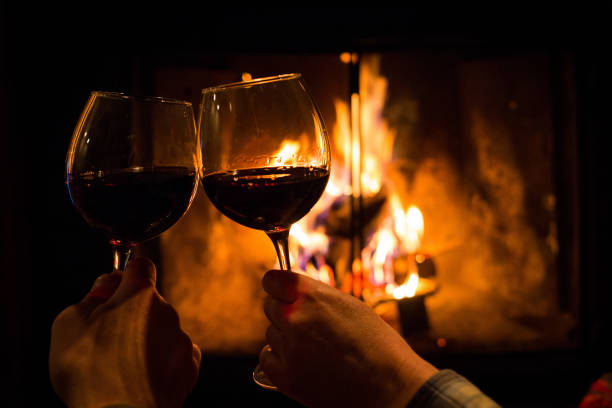 Couple holding pair of glasses with wine at fire pit stock photo