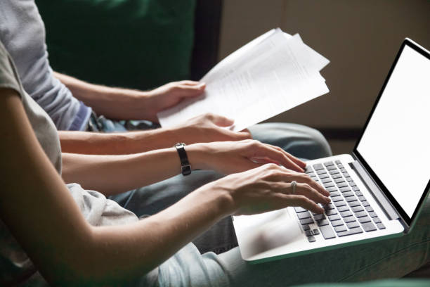 Couple holding reading documents at home with laptop, close up Close up of couple searching online information about legal document details with laptop, family studying important contract terms and conditions typing filling internet application form on website human body part stock pictures, royalty-free photos & images